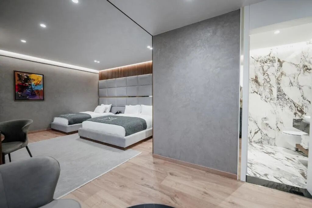 Un dormitorio moderno con una cama grande, una cama más pequeña y una zona de estar con sillones.