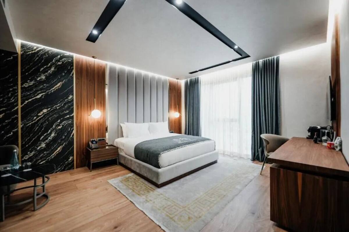 Una camera da letto moderna con un letto, comodini, una scrivania e una sedia.
