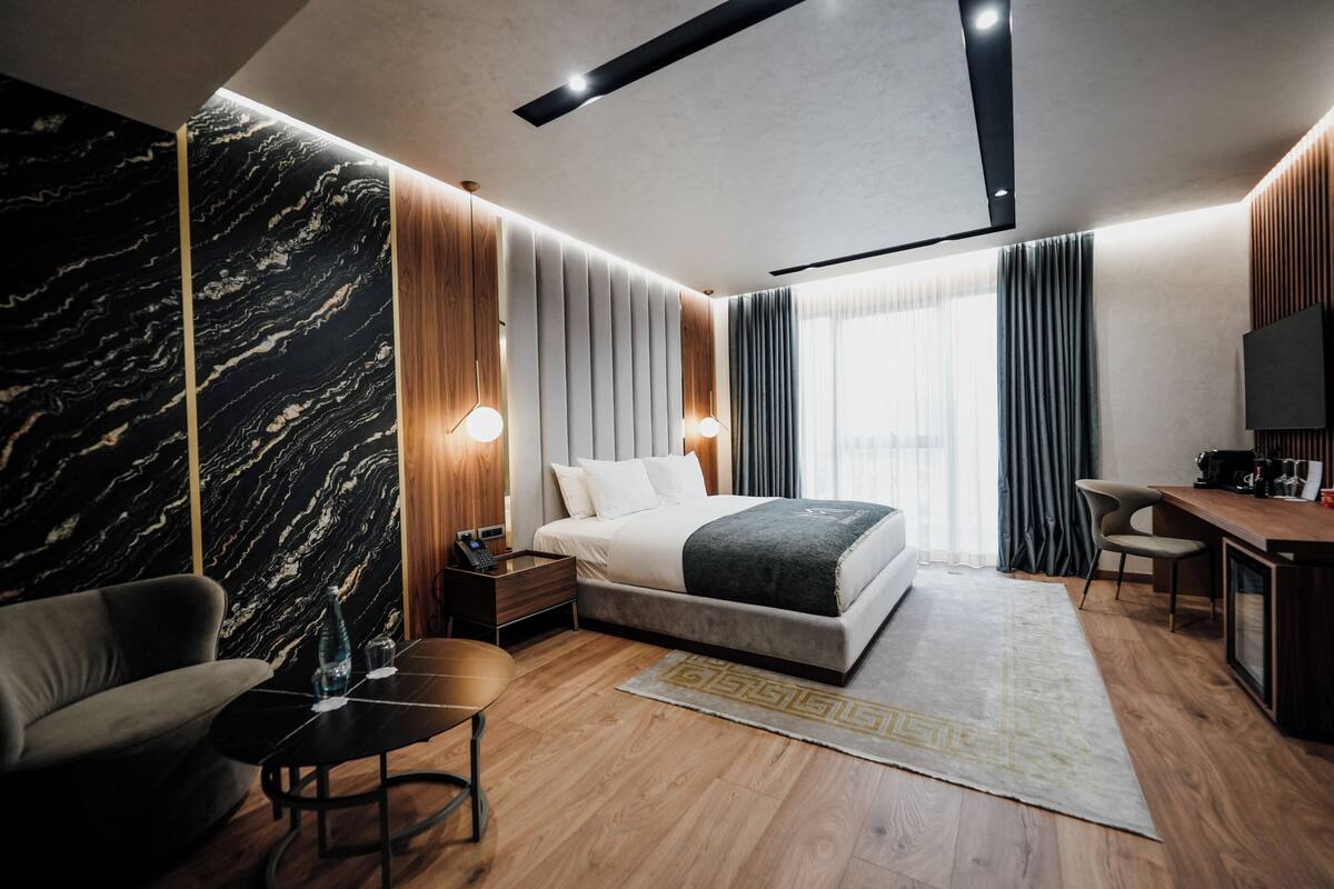Una moderna camera d'albergo con un letto, una scrivania, una sedia e una grande finestra.