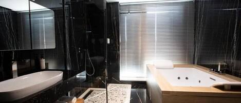 Un baño moderno con un espejo grande, un lavabo blanco, un mueble de tocador de madera, una bañera y una zona de ducha.