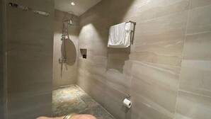 A modern bathroom with a shower, a toilet, and a towel rack.