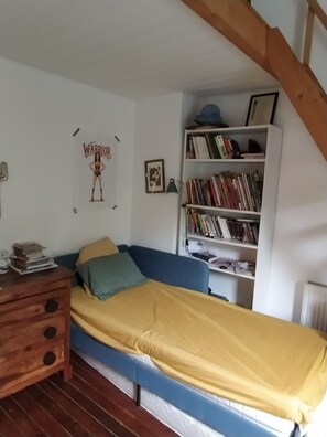 A bedroom with a single bed, a wooden nightstand, a bookshelf, and a sloped ceiling. - Maison Familiale, au Calme, a 10 min des Gares (La Madeleine)