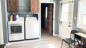 A laundry area with a washing machine and dryer, wooden cabinets, and a door leading to another room.