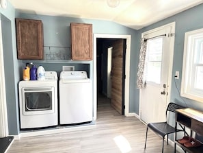 A laundry area with a washing machine and dryer, wooden cabinets, and a door leading to another room.