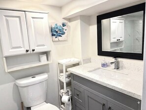 Een badkamer met toilet, wastafel, spiegel en een plank met handdoeken.