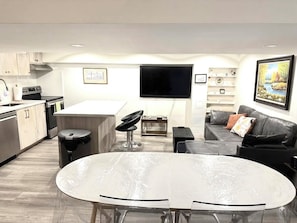 Een moderne keuken met een eethoek, een flatscreen televisie en een bank.