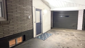 A garage with a closed grey door, a blue door, and a concrete floor with a patterned mat.