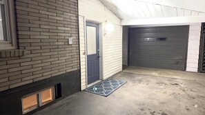 Un garatge amb una porta tancada de color gris, una porta blava i un sòl de formigó amb un estriat.