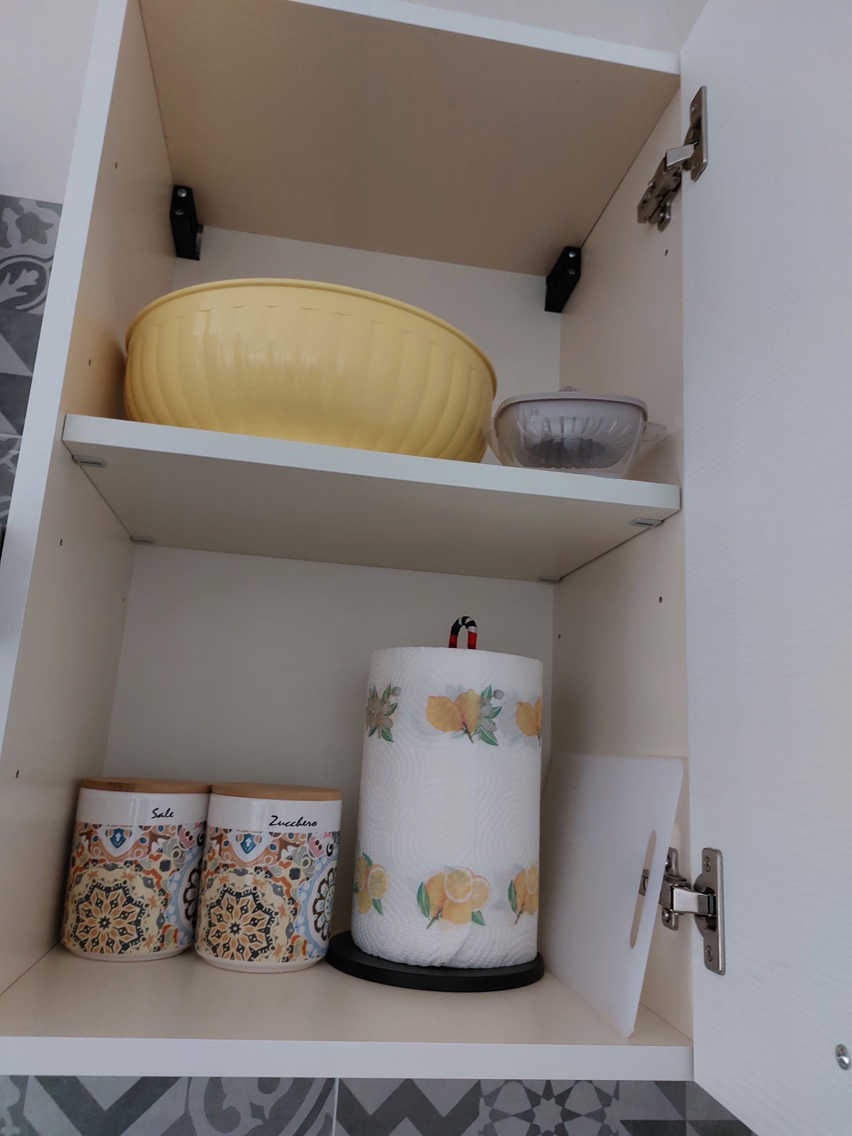 Ein Schrank mit einer gelben Schüssel, einer klaren Schüssel und verzierten Behältern.