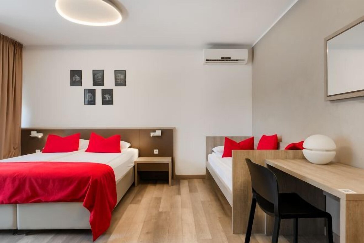 A hotel room with a bed, bedside tables, a desk, and a chair.