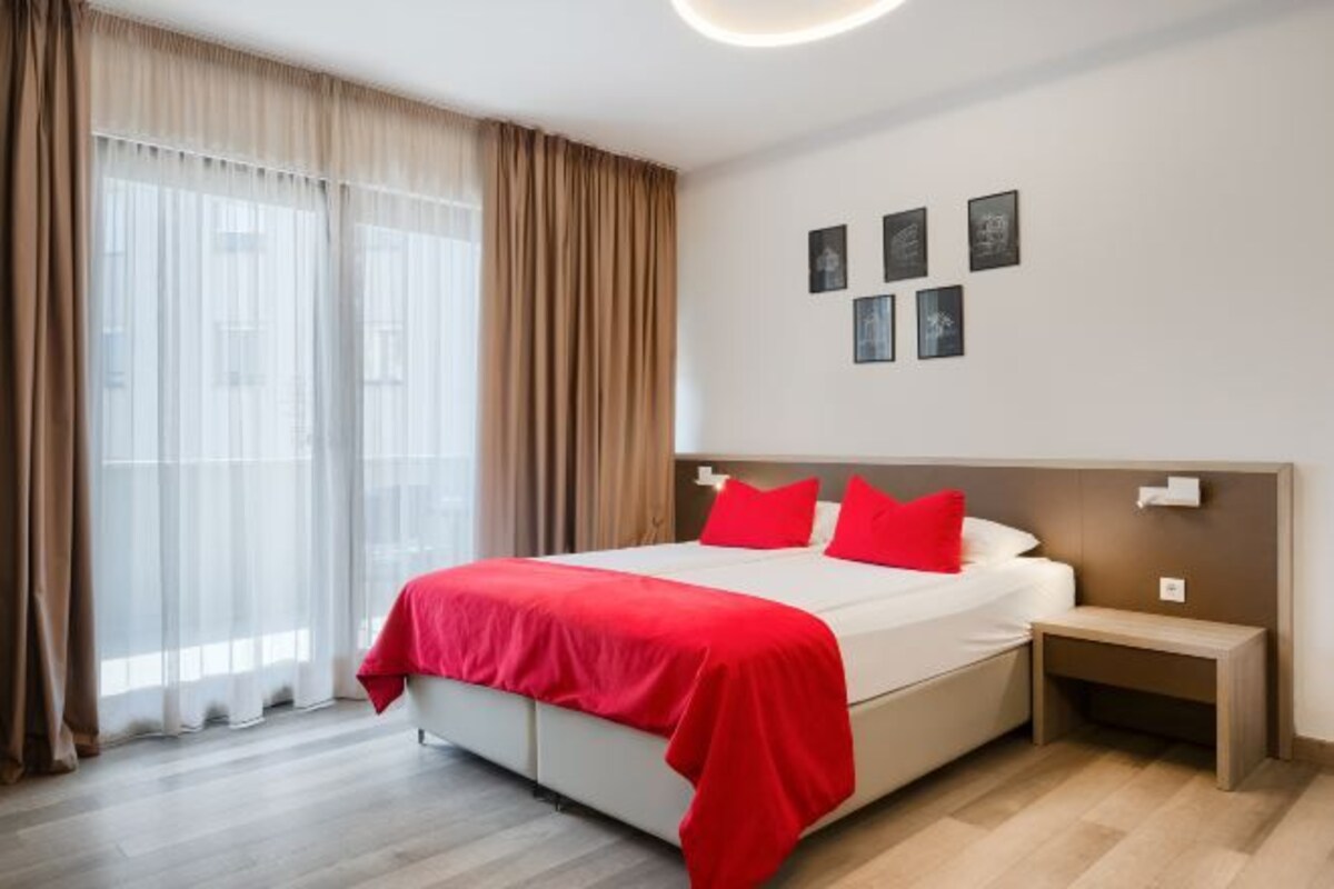 A hotel room with a bed, bedside tables, and curtains.