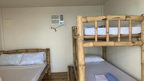 Une chambre avec deux lits superposés, un climatiseur fixé au mur et une prise électrique sur le mur.