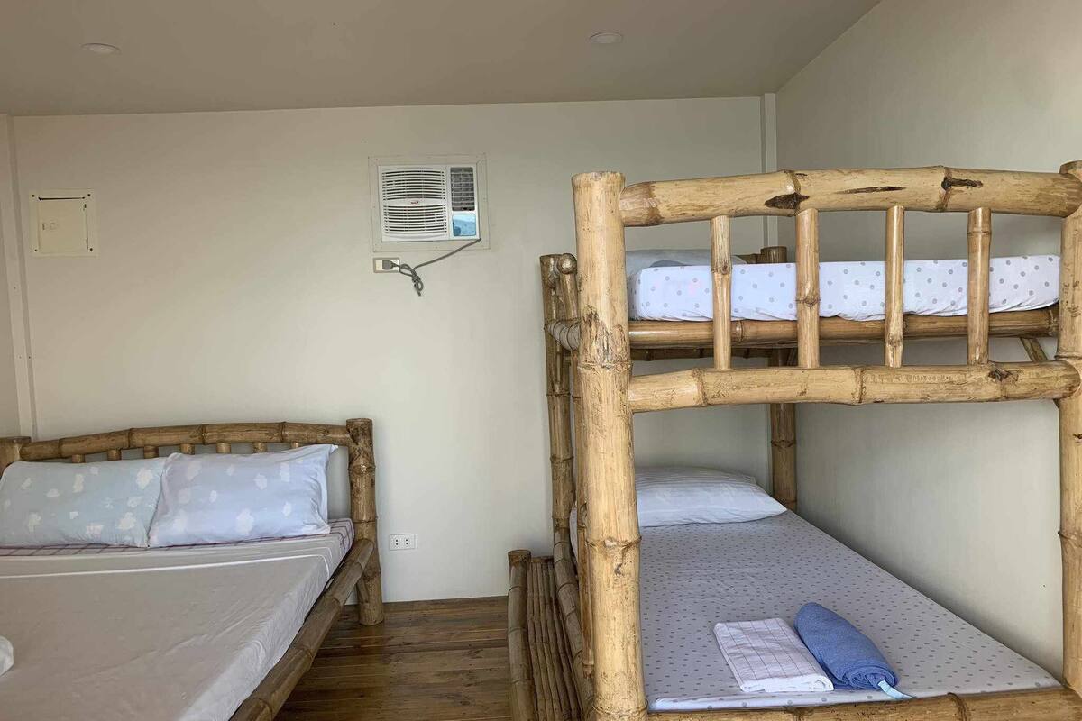 Una habitación con dos literas, aire acondicionado de pared y un enchufe en la pared.