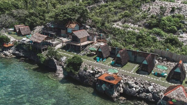 Un village côtier avec des maisons aux toits de chaume, des eaux cristallines et un paysage rocheux.