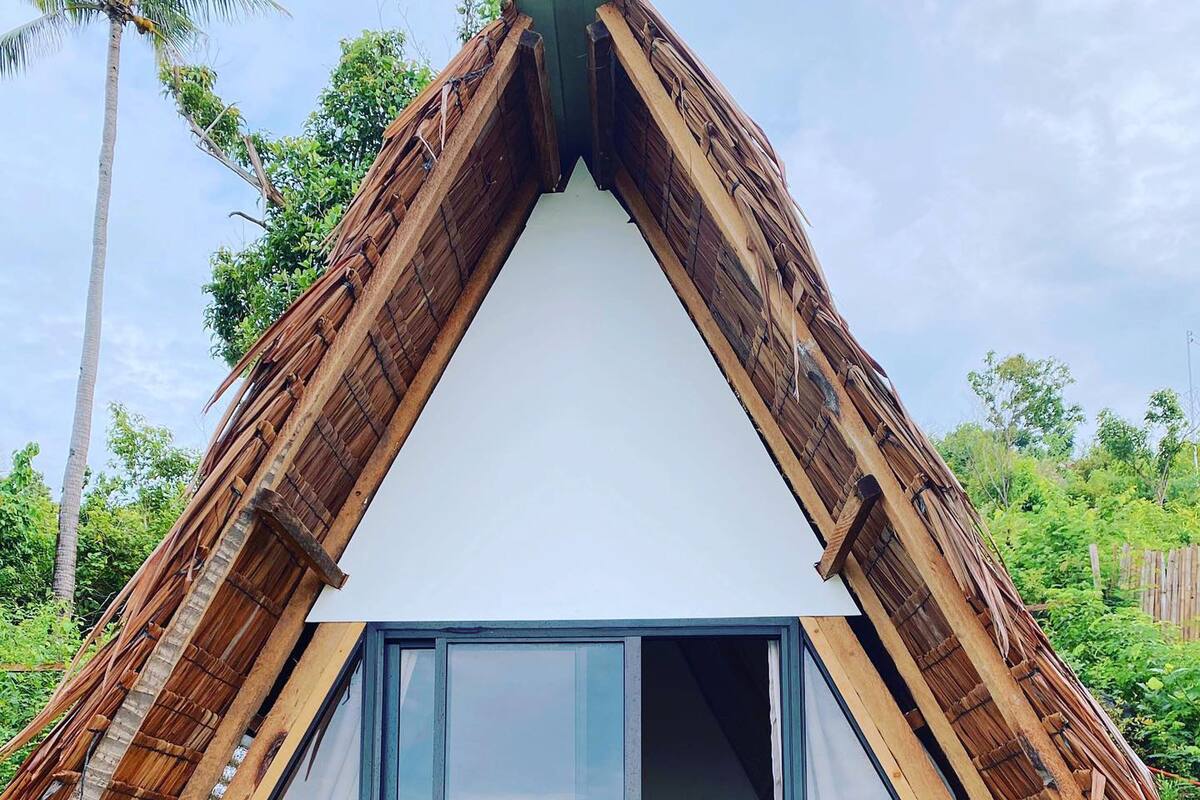 Una pequeña estructura de madera con techo inclinado y ventanas grandes de vidrio.