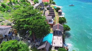 Une propriété située sur la côte, dotée d’une piscine, de plusieurs bâtiments de style bungalow et d’un quai pour bateaux.