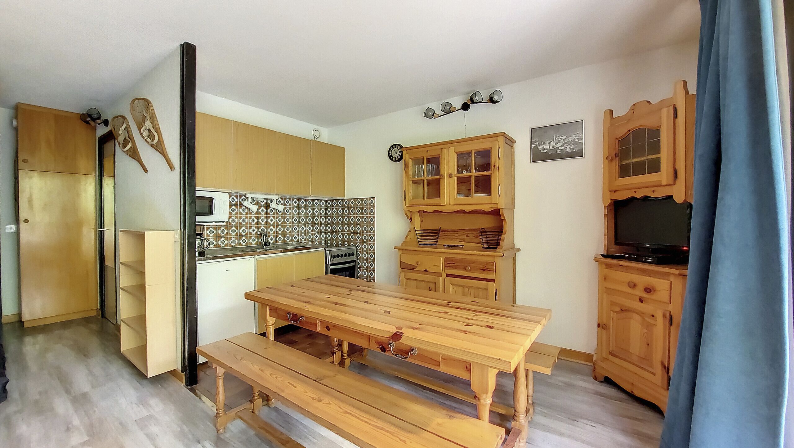 Une cuisine compacte avec des meubles de rangement en bois, une table à manger en bois et un four encastré.