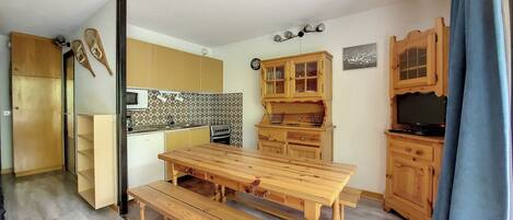 Une cuisine compacte avec des meubles de rangement en bois, une table à manger en bois et un four encastré.
