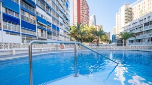 Une piscine équipée d’un escalier en métal, entourée d’immeubles à plusieurs étages dotés de balcons.