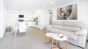 Un salon moderne avec un canapé beige, une table à manger en verre et une table basse blanche.