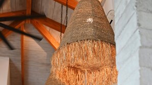 A kitchen with a black refrigerator, a wooden cabinet, and a hanging woven light fixture. - Muza Beach Villa Steps to Most Requested Beach! (Puntarenas Province)