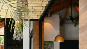 A modern living room with a sofa, a dining area with chairs, and a hanging light fixture. - Muza Beach Villa Steps to Most Requested Beach! (Puntarenas Province)
