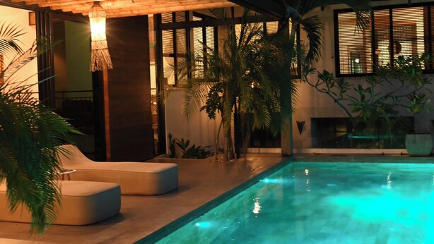 A modern outdoor pool area with a thatched roof, lounge seating, and tropical plants. - Muza Beach Villa Steps to Most Requested Beach! (Puntarenas Province)
