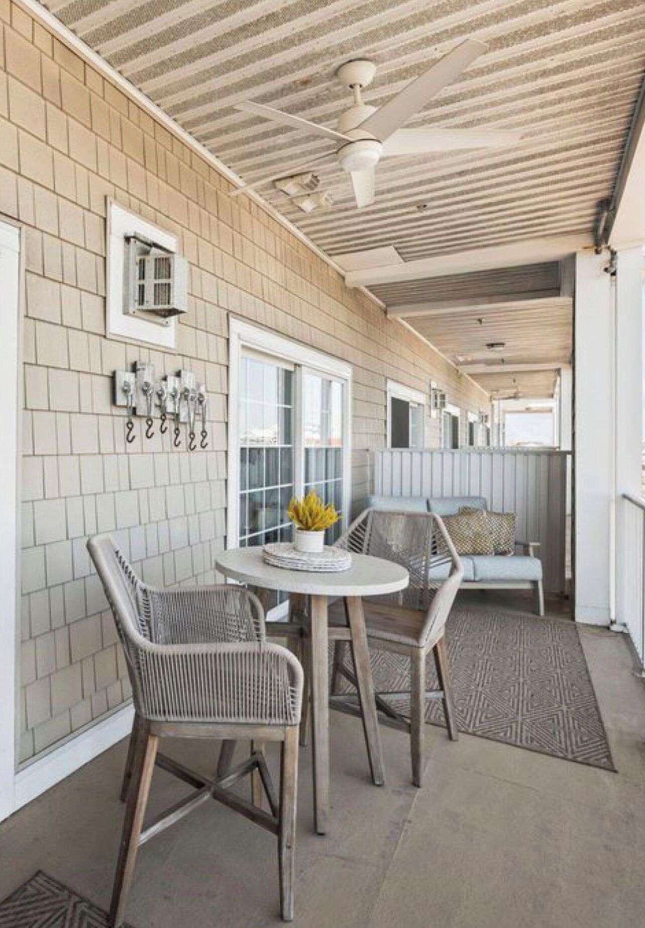A covered outdoor area with a table and chairs, a ceiling fan, and a bench.