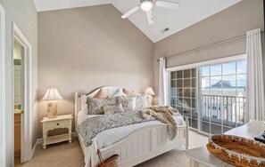 Ein Schlafzimmer mit Bett, Nachttischen, Deckenventilator und einem großen Fenster mit Blick.