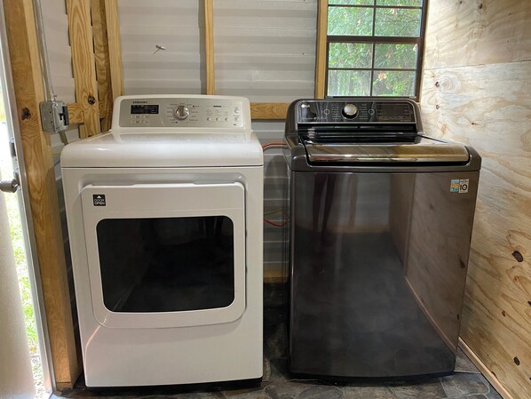 A compact laundry room with a white washer and dryer, and a black refrigerator. - SalemOasis Glamping RVnear Silver Spring State Park (Ocala)