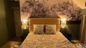 Un dormitorio con cama, dos lámparas de noche, un mural en la pared y una mesita de noche.
