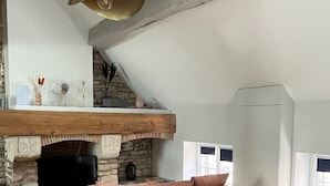 Un loft moderno con chimenea de piedra, un sofá rosa y una mesa de comedor de vidrio.