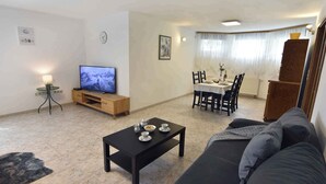 A living room with a TV, a dining table, and a sofa. - Studio with dishwasher near the beach (Umag)