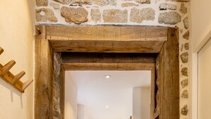 A stone archway leading to a hallway with wooden flooring and framed pictures on the walls.