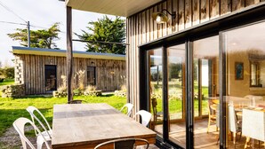 A wooden dining table with chairs, a stone wall, and a glass door leading to an outdoor area.