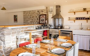 A cozy kitchen with stone walls, wooden furniture, and modern appliances. - Gîtes de Lézinadou - 8 personnes - Plomeur La Torche (plomeur)