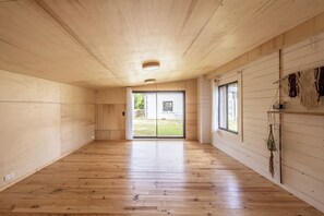 A spacious room with wooden floors and walls, a large sliding glass door leading to an outdoor area, and a ceiling with recessed lighting. - Gîtes de Lézinadou - 6 personnes - Plomeur La Torche (plomeur)
