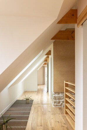 A modern interior with a sloped ceiling, wooden beams, a stone wall, and a wooden bench. - Gîtes de Lézinadou - 6 personnes - Plomeur La Torche (plomeur)