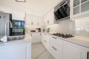 A modern kitchen with white cabinetry, a stainless steel refrigerator, a built-in oven, a gas stove, and a microwave. - Green Hills Family-Friendly Luxury Villa - Fethiye (Fethiye)