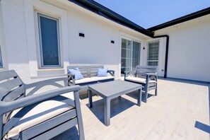 Ein Außenbereich mit zwei Sofas, zwei Sesseln, einem kleinen Tisch und einem Fenster mit Blick.