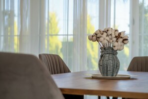 A table with a vase of cotton plants in a textured ceramic pot.