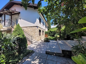 Une maison à deux étages avec une façade en pierre, un balcon et un jardin bien entretenu.