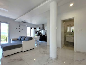 Una sala de estar moderna con sofá, comedor, cocina y una columna grande.