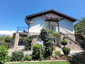 Une maison à deux étages avec une façade en pierre, un balcon et un jardin bien entretenu.