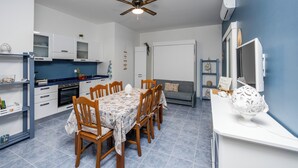 Eine kleine Küche mit Essbereich, weißen Schränken, einem Deckenventilator und einer blauen Akzentwand.