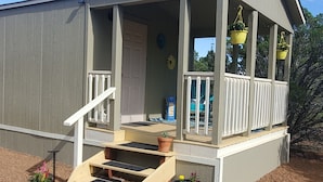 A two-story house with a porch, a staircase, and potted plants. - Peaceful getaway for 2, dog friendly (Concho)