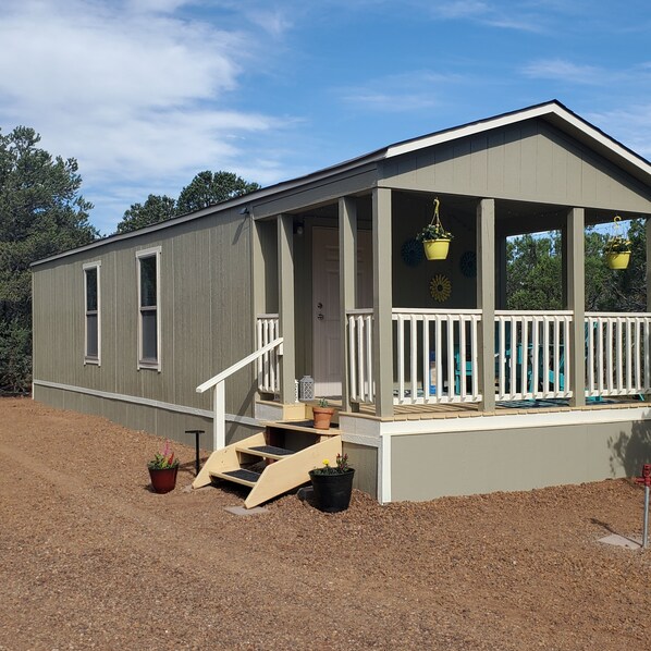A single-story building with a porch, a small set of steps, and potted plants.