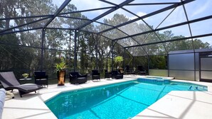 Una piscina al aire libre techada con sillas de descanso y plantas en macetas.