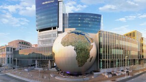 A modern building with a large globe sculpture in front, surrounded by glass facades and a clear sky. - Modern And Spacious Studio Retreat (Raleigh)