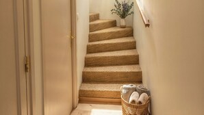 A staircase with a woven carpet, a wicker basket with towels, and a hanging light fixture. - VILLA EDOUARD - 180m2 in the heart of nature - 20min Disney - 7min Airport (Claye-Souilly)